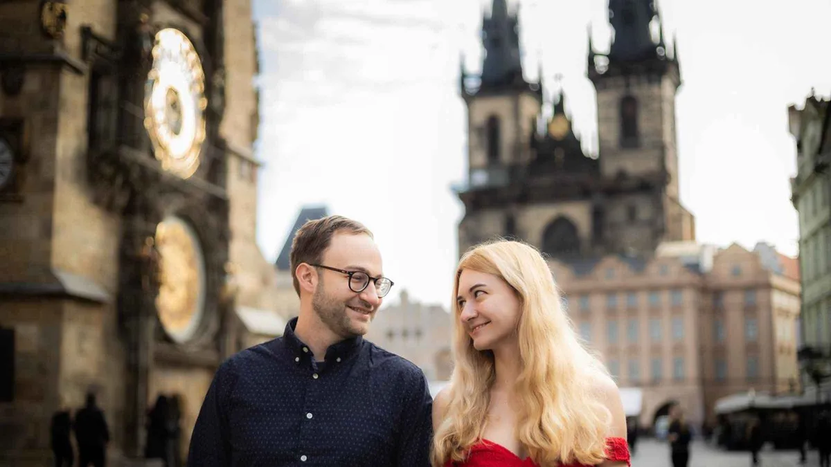 A photographer directing a couple beside the Astronomical Clock during a Prague photoshoot in the Old Town, Prague