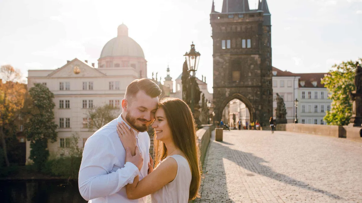 A couple posing on Charles Bridge at golden hour during a romantic Prague couples photoshoot, Prague